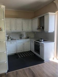 uma cozinha com armários brancos e um forno com placa de fogão em Sea View House Voula em Atenas