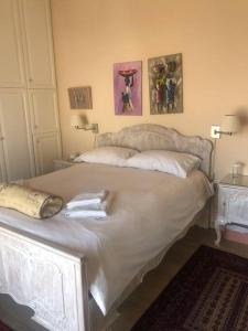 een wit bed in een slaapkamer met twee foto's aan de muur bij Sea View House Voula in Athene