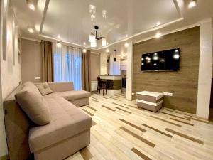 a living room with a couch and a television on a wall at 1-кімн Стильні апартаментами біля Корпусного саду ,Стадіон"Динамо" in Poltava