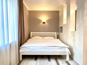 a bedroom with a white bed and a window at 1-кімн Стильні апартаментами біля Корпусного саду ,Стадіон"Динамо" in Poltava