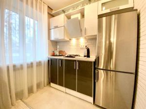 a kitchen with a stainless steel refrigerator and white cabinets at 1-кімн Стильні апартаментами біля Корпусного саду ,Стадіон"Динамо" in Poltava