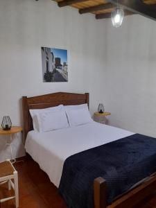 Un dormitorio con una gran cama blanca y dos mesas. en Casa do Celeiro - Monsaraz, en Monsaraz