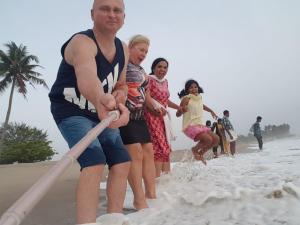 um grupo de pessoas brincando na areia na praia em White Sands Homestay em Turavūr