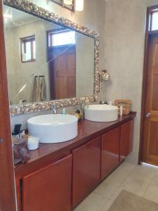 La salle de bains est pourvue de 2 lavabos et d'un grand miroir. dans l'établissement Harbour View House, à Port Elizabeth