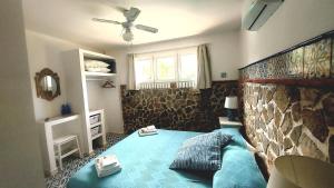 a bedroom with a blue bed with a stone wall at VFH Villa Flavia Eco B&B - 50 metri dal mare in Santa Flavia