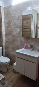 Irini Apartments في كيراموتي: حمام مع حوض ومرحاض ومرآة