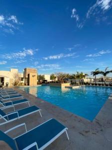 una piscina con sillas azules y palmeras en Beautiful new house with pool club, en Los Bledales