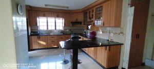 cocina con armarios de madera y encimera negra en Sthembile's guest house, en Richards Bay