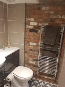 a bathroom with a white toilet and a brick wall at The Mews in Alderley Edge