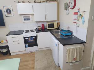 a small kitchen with white cabinets and a sink at HAVEN STUDIO GROUND FLOOR in Whitehaven