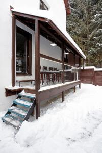 a house with a porch in the snow at Caraiman Hive in Buşteni