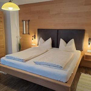 uma cama grande com lençóis brancos e almofadas em Lizzi Mountain Apartments em Schwangau