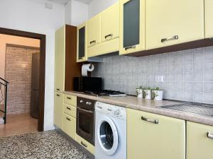een keuken met gele kasten en een wasmachine bij Casa del Ciliegio in Valeggio sul Mincio