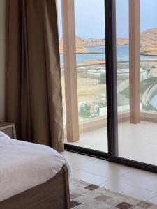 a bedroom with a large window looking out at the ocean at W muscat bay in Muscat