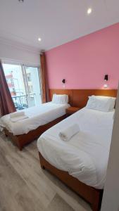 2 camas en una habitación con una pared de color rosa en Residencial Condado en Faro