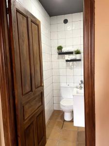 a bathroom with a toilet and a wooden door at La Llamera in Ortiguero