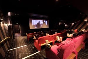 a theatre with red chairs and a projection screen at Central Mews House Altrincham in Altrincham