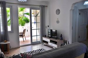 een woonkamer met een televisie en een deur naar een patio bij Hisarönü Love Vacation Apartment in Fethiye