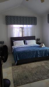 a bedroom with a large bed with a blue blanket at Caribbean Estates, 10 mins from the Beach, Beautiful Gated Community in Portmore