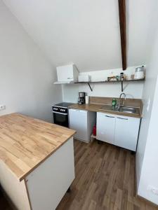 una cucina con armadietti bianchi e pavimenti in legno di Au bord de la mer Appartement 2 personnes a Saint-Benoît-des-Ondes