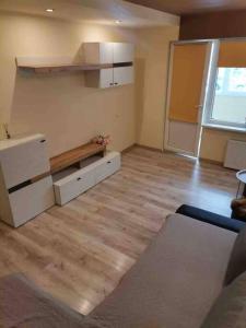 een lege keuken met witte kasten en een houten vloer bij Cozy two-room apartment in Liepāja