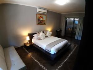 1 dormitorio con 1 cama blanca grande y 1 sofá en Tapologo Lodge, en Zeerust