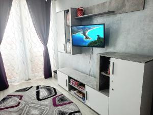 ein Wohnzimmer mit einem Fernseher an der Wand in der Unterkunft Apartament BriFla Comfort Mureș in Târgu Mureș