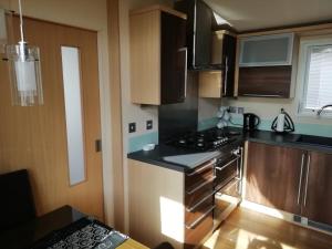 a kitchen with wooden cabinets and a stove top oven at Exe View Retreat in Dawlish Warren