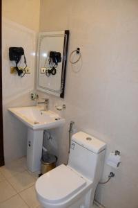 een badkamer met een toilet, een wastafel en een spiegel bij فندق اللؤلؤة الذهبي in Sīdī Ḩamzah