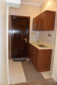 a kitchen with a wooden door and a sink at فندق اللؤلؤة الذهبي in Sīdī Ḩamzah