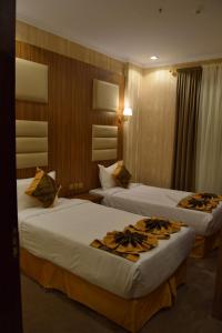 - deux lits dans une chambre d'hôtel avec deux couvre-lits dans l'établissement فندق اللؤلؤة الذهبي, à Sīdī Ḩamzah