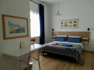 Un dormitorio con una cama con almohadas azules y una mesa. en Domo Sul Porto en Stintino