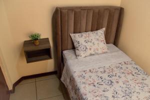 Cama pequeña con almohada y mesita de noche en Hermoso Departamento dentro de un Condominio, en Chiclayo