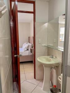 uma casa de banho com um lavatório, um espelho e uma cama em Hermoso Departamento dentro de un Condominio em Chiclayo