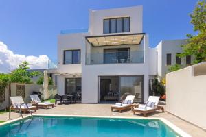 a villa with a swimming pool in front of a house at 5star Villa Harmony w heated pool, Gym, Spa, Sauna in Skalánion