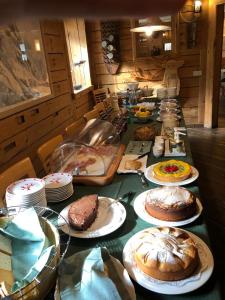 een lange tafel met gebak en gebak op borden bij Valbruna Inn Bed & Breakfast in Valbruna