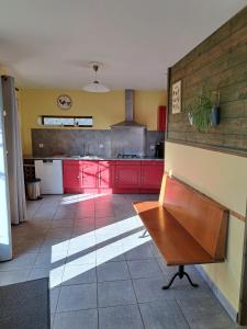 a kitchen with red cabinets and a table in it at Gite D'étape Et De Séjour Les Sables in Brégnier-Cordon