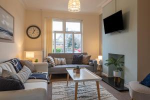 ein Wohnzimmer mit einem Sofa und einem Tisch in der Unterkunft Hope House Chester Sleeps 6 by Heritage Stays in Hough Green