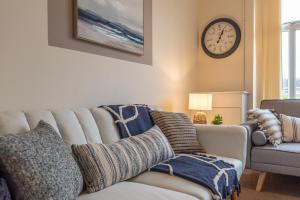 a living room with a couch and a clock on the wall at Hope House Chester Sleeps 6 by Heritage Stays in Hough Green