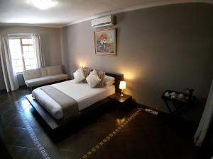 1 dormitorio con 1 cama y 1 sofá en Tapologo Lodge, en Zeerust