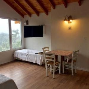 1 dormitorio con 1 cama, mesa y sillas en Puerto Esmeralda ESPECTACULAR DEPTO CON VISTA AL LAGO NAHUEL HUAPI en Villa La Angostura