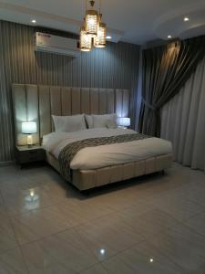 een slaapkamer met een groot bed en een kroonluchter bij شقة فاخرة حي الرمال in Riyad