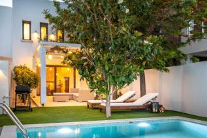 une piscine avec des chaises et un arbre à côté d'une maison dans l'établissement Romantic, homely Villa Aura w heated pool, à Skalánion