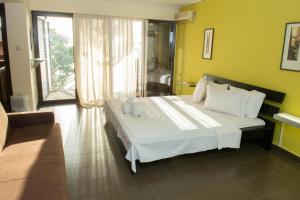 a bedroom with a white bed and a couch at Tajo VIllas in Athani