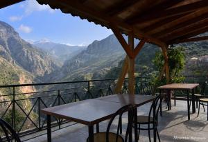 un patio con mesas y sillas y vistas a las montañas en Φαράγγι Καρδαμύλης en Exochori