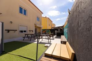 a patio with picnic tables and a wall with grass at Pineapple Surf House in Peniche
