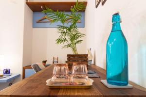 a blue bottle and two glasses on a wooden table at Trigu & Mangoni in Cagliari