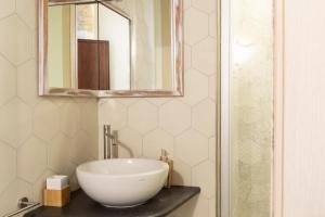 een badkamer met een witte wastafel en een spiegel bij Trigu & Mangoni in Cagliari