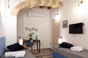 twee bedden in een kamer met een tv aan de muur bij Trigu & Mangoni in Cagliari