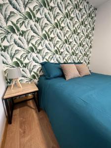 ein Schlafzimmer mit einem blauen Bett und einem Wandbild in der Unterkunft Les gîtes de la bergerie in Meximieux